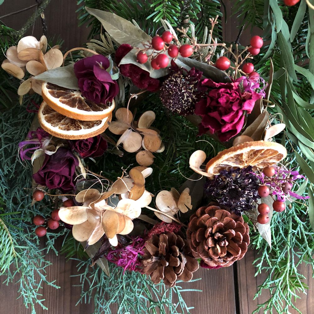 赤系の花や実、オレンジの輪切りをあしらったリース。